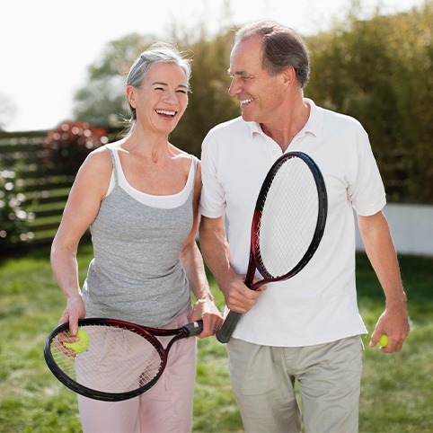 Older man and woman playing tennis after treatment for foot and ankle injuries
