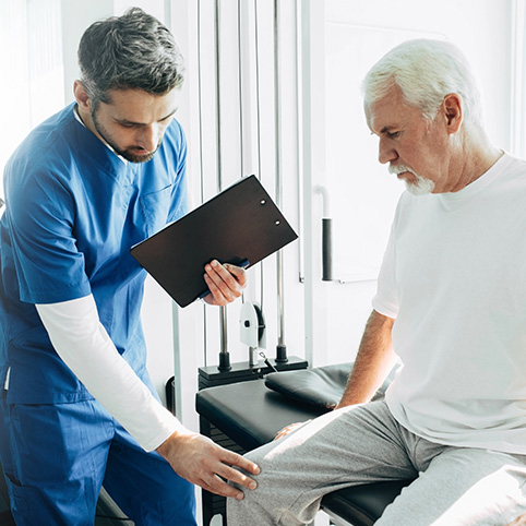 Doctor examining older man with knee arthritis