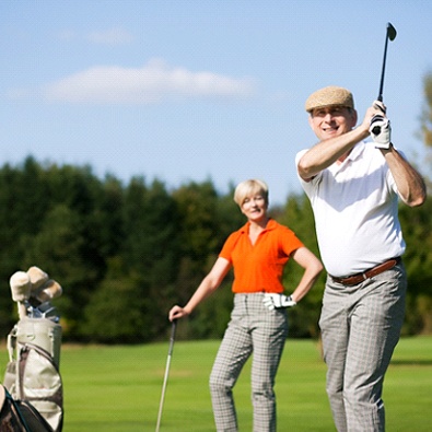 middle-aged man playing golf with wife 