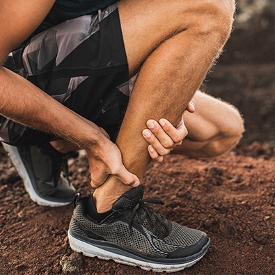 Man with Achilles tendinitis holding ankle