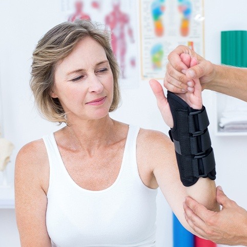 Doctor examining woman's arm with wrist brace