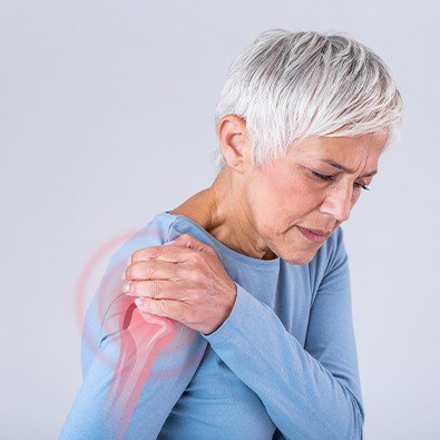 Woman experiencing calcific tendinitis symptoms holding shoulder