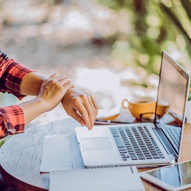 woman holding painful wrist at desk 