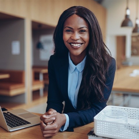 Business woman in office smiling after carpal tunnel syndrome treatment