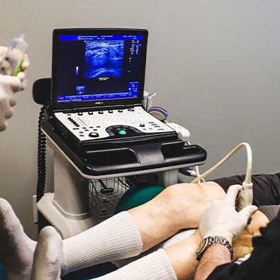 Doctor using ultrasound machine to examine patient's knee