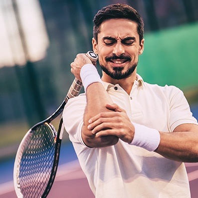 Man with tennis elbow holding arm in pain