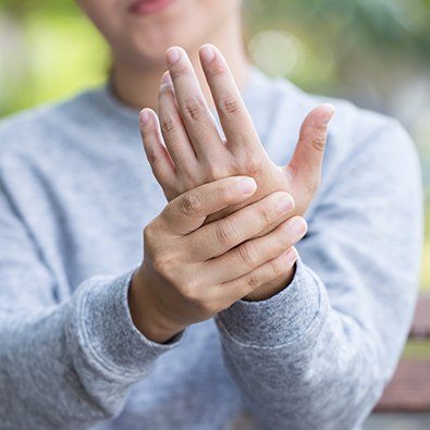 Patient with arthritis in hands holding her hand up in pain