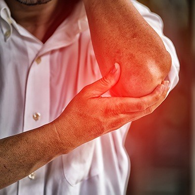 Man experiencing elbow joint instability holding elbow