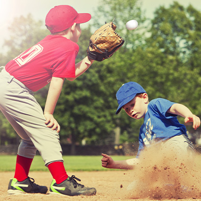 Two young boys playing baseball after little league elbow treatment