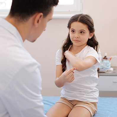 Young girl with little league elbow pointing to painful area