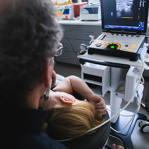 Dr. Tortland using ultrasound to examine patient with neck pain