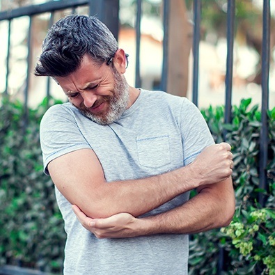 Man with pitcher's elbow holding arm in pain