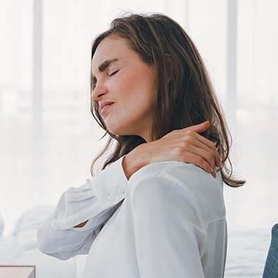 Grimacing woman with joint instability and impingement holding neck