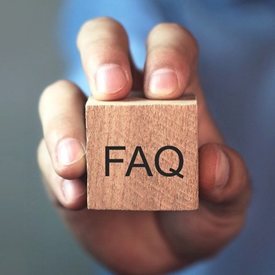 hand holding a wooden block that says “FAQ”