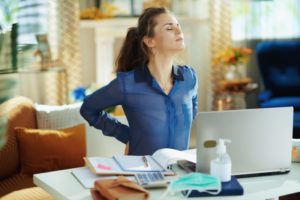 woman stretch back while sitting at desk 