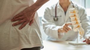man with back pain speaking to a doctor