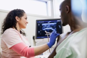 Medical professional using ultrasound on man’s shoulder
