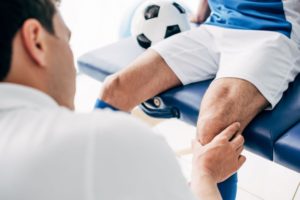 Sports medicine doctor examining patient’s knee