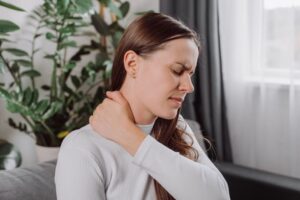 Woman touching her neck, wearing pained expression
