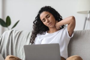 Woman sitting at her computer, struggling with neck pain